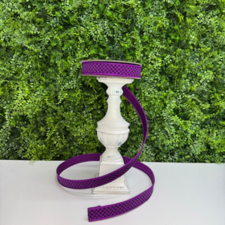 Purple and black checked Farrisilk ribbon on a white pedestal against a green leafy background
