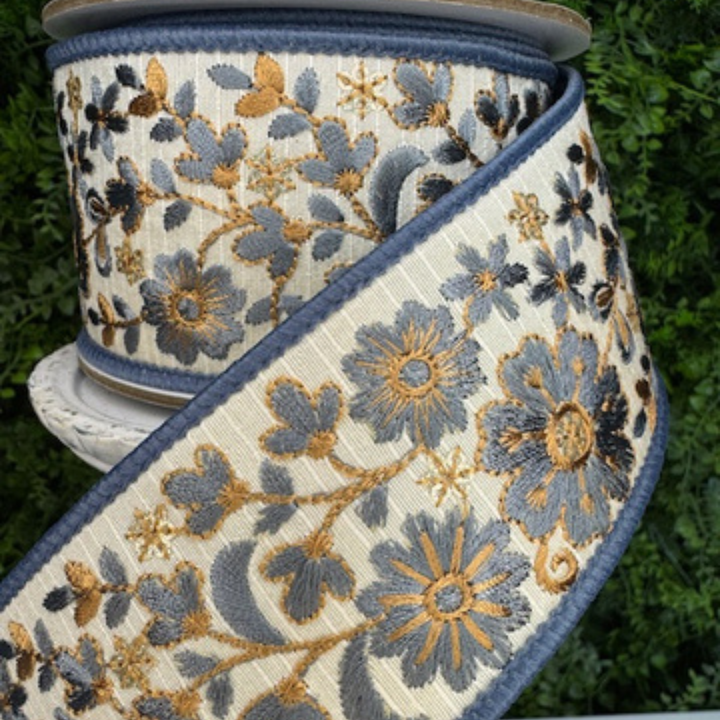 Spool of Farrisilk steel blue floral embroidery thread ribbon with blue and gold design on a green background