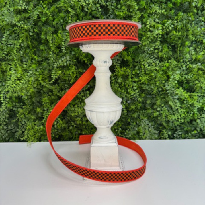 Decorative Farrisilk ribbon in an orange and black check for Halloween against green hedge background