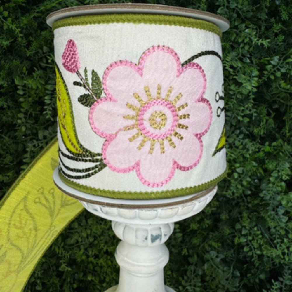 Decorative Farrisilk floral ribbon in pink, green and yellow with floral design against a green leafy background