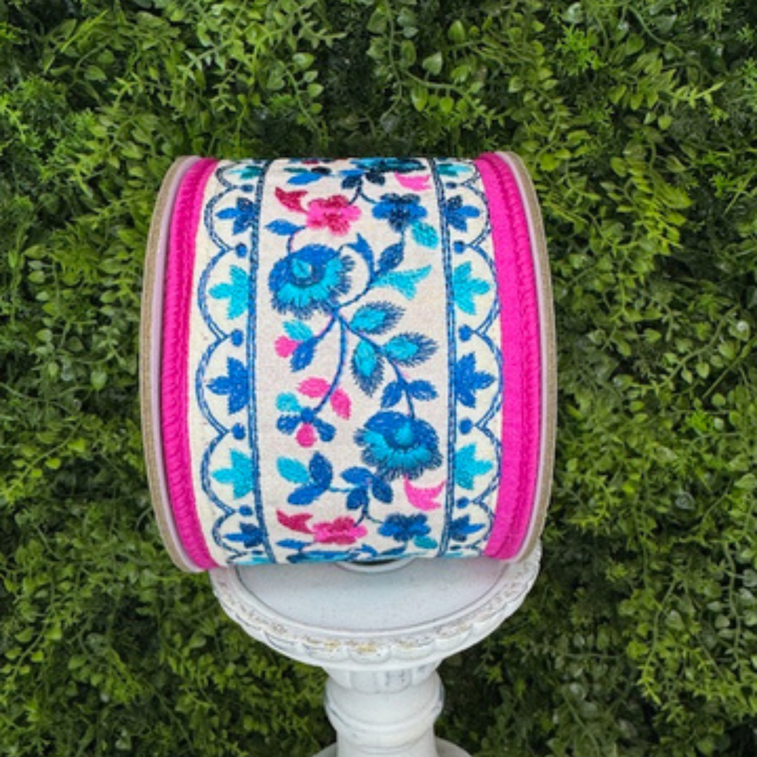 Decorative spool of ribbon with floral patterns on a green grass background