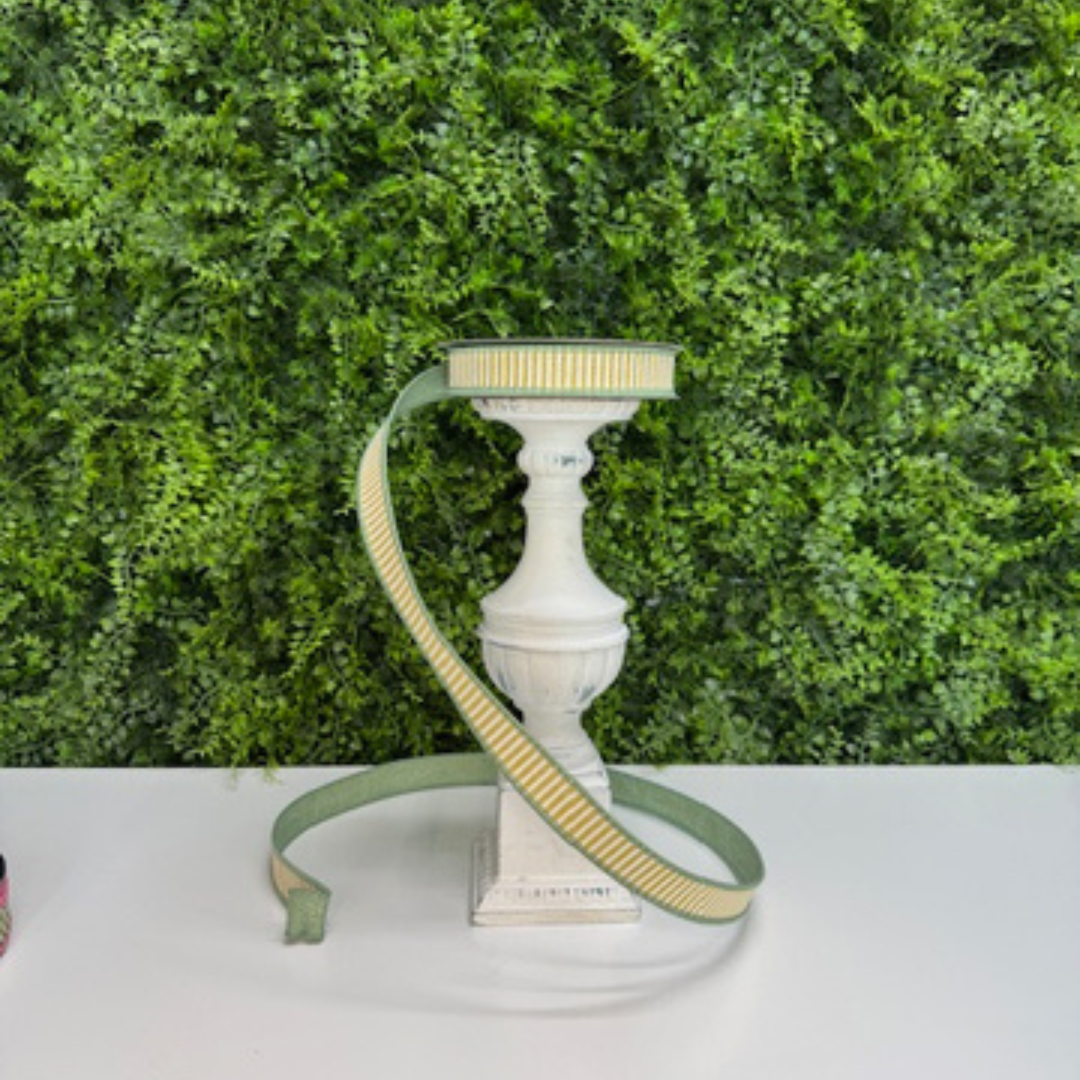 Farrisilk Yellow and white striped ribbon with green back and edging on a white surface against a green leafy background