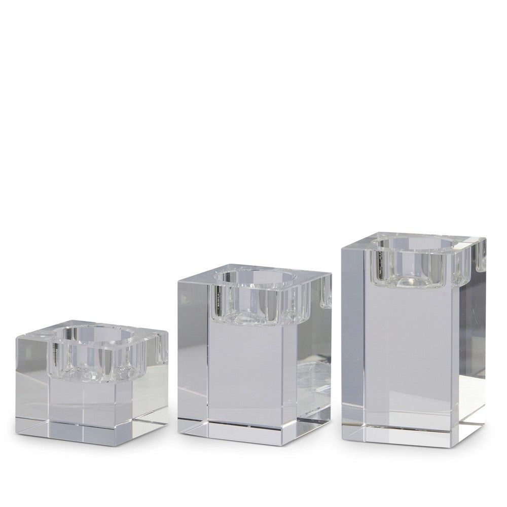 Three clear glass candle holders of different sizes on a white background