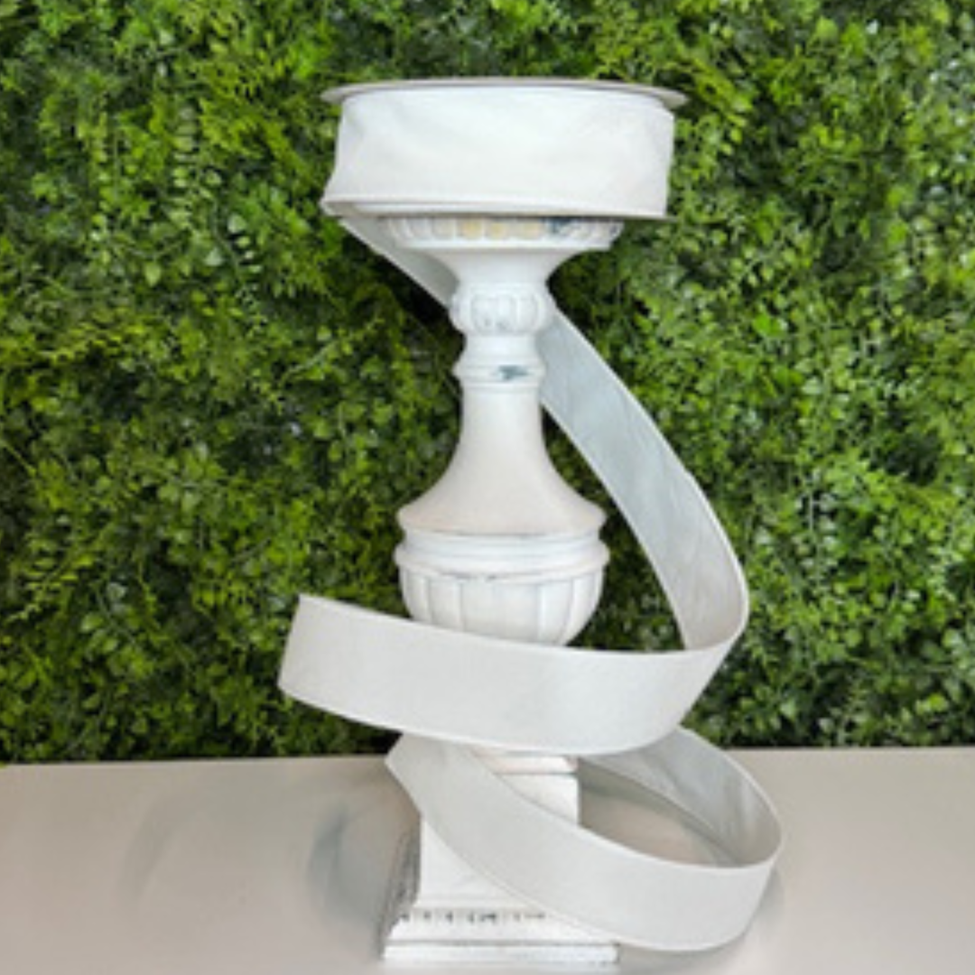 White decorative ribbon against a green hedge background