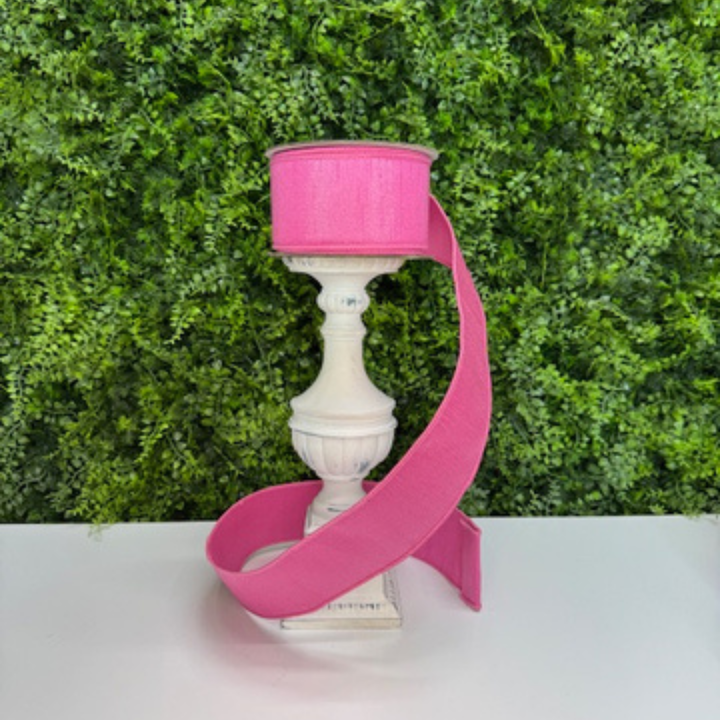 Decorative Farrisilk pink ribbon against a green foliage background