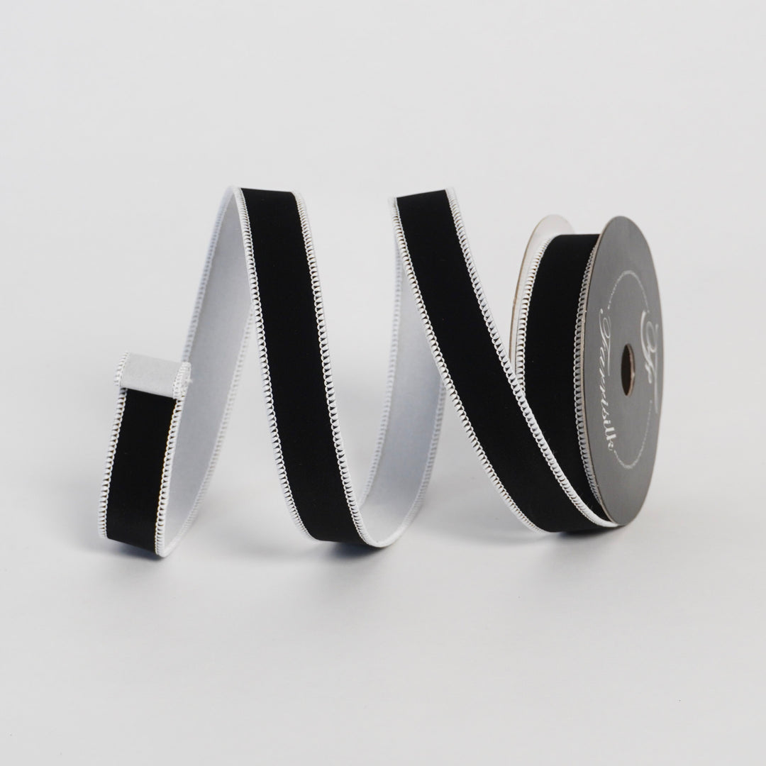 Black and white ribbon on a spool against a light gray background