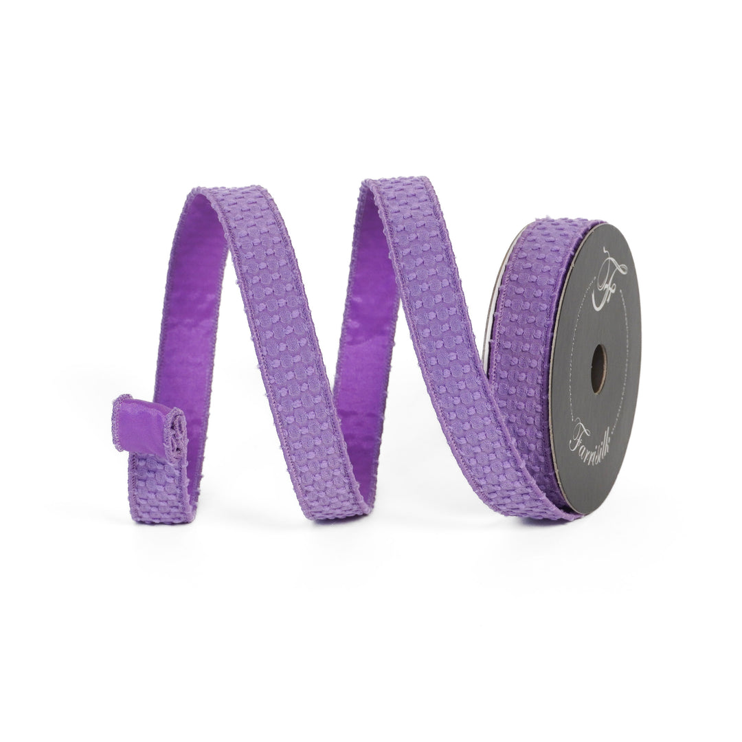 Purple ribbon on a spool with a white background