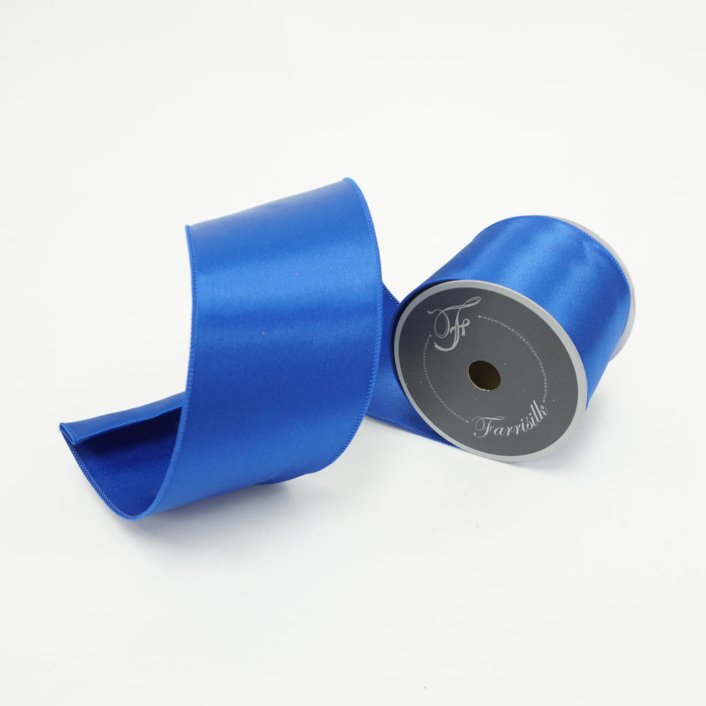 A roll of royal blue satin wired ribbon with a portion unrolled to show the color and texture.
