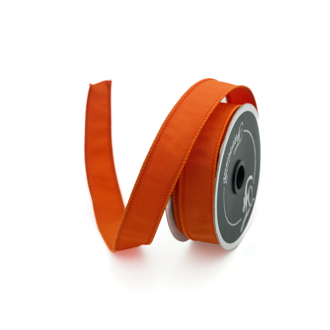 Orange ribbon on a spool with a white background