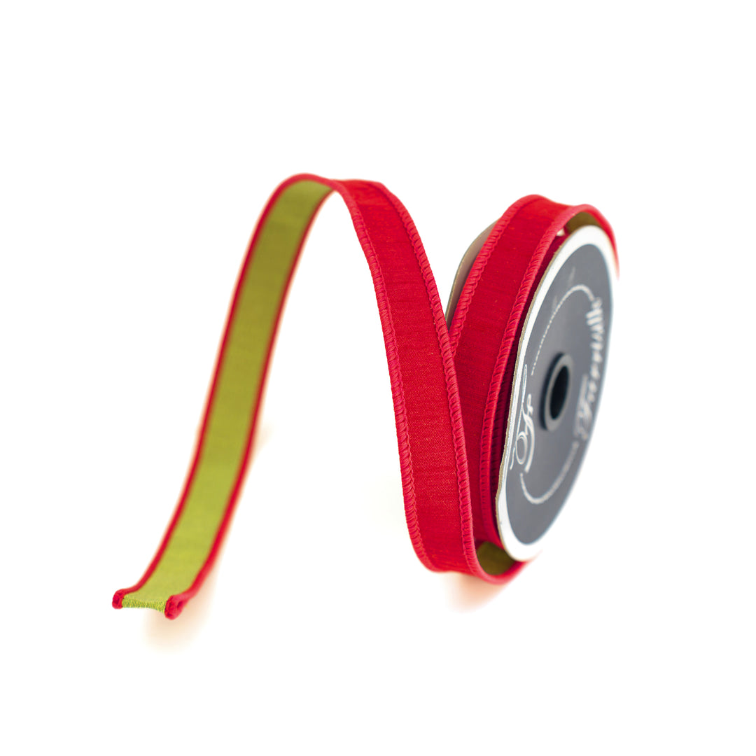 Red ribbon with green back on a spool with a white background