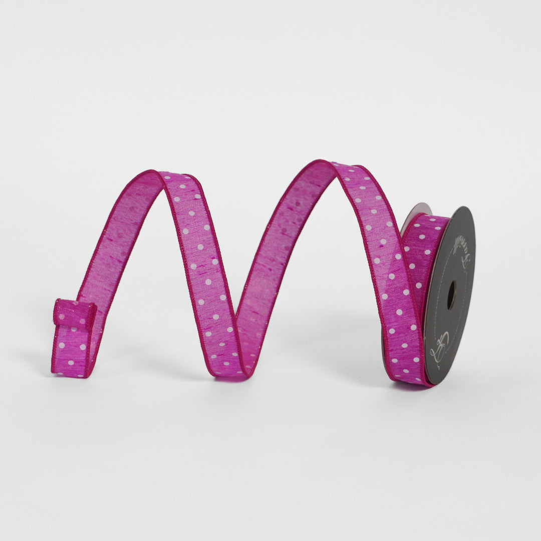 Spool of Hot pink ribbon with white polka dots on a light gray background
